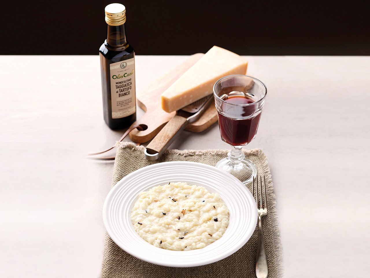 Teller mit Trüffel-Risotto, ein Glas Wein, Parmigiano Käse und Flasche Trüffelöl