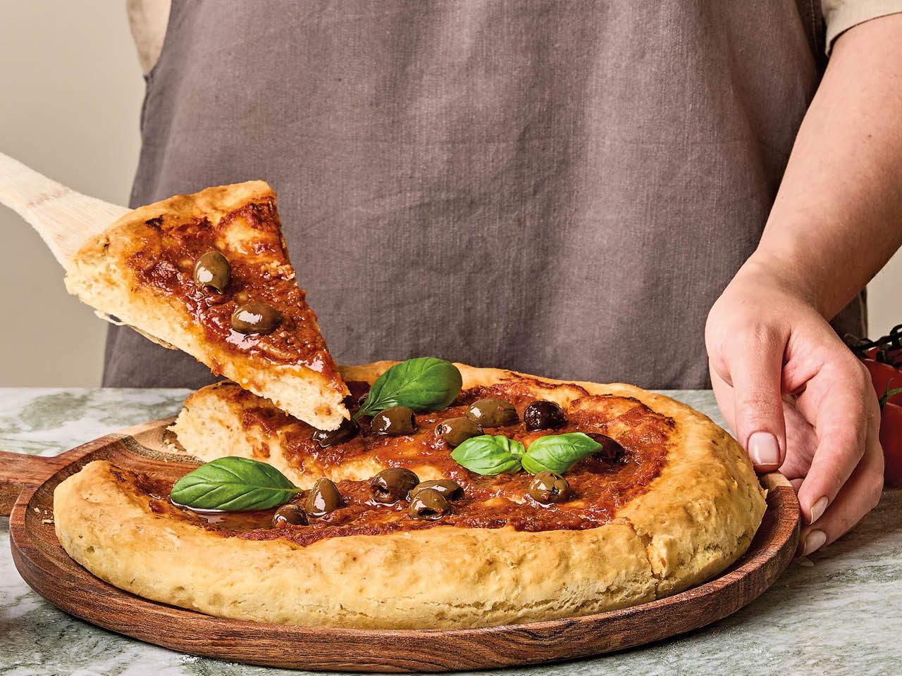 Pizza mit entsteinten Oliven und Basilikum