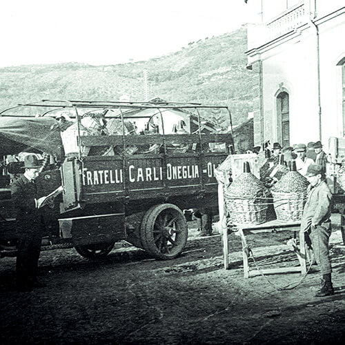 Historisches Foto: Carli Öl in Korbflaschen, am Bahnhof bereit für den Versand per Zug an die Kunden